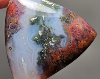 Puede incluir: Un cabujón triangular de ágata con un patrón blanco, verde y rojo. La piedra tiene una superficie pulida y está engastada en un engaste plateado.