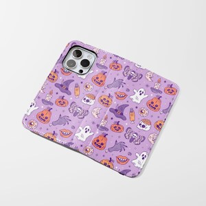 May include: A purple phone case with a Halloween-themed pattern. The design includes orange pumpkins, white ghosts, witch hats, candles, and other spooky illustrations. The case is open, revealing the phone's camera.