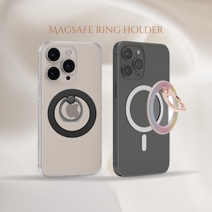 May include: Two iPhone cases with a black and a sparkly pink ring holder attached to the back. The text "MAGSAFE RING HOLDER" is displayed at the top of the image.