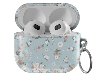 May include: A light blue Airpods case with a floral pattern. The case has a small white light on the front and a silver ring attached to the side.