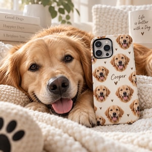 May include: A cream-coloured smartphone case featuring a repeating pattern of golden retriever faces, small brown hearts, and the name Cooper printed in a script font. The case has a black camera lens cutout and a smooth, matte-finish surface.
