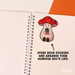 An opened page of a spiral bound book showing a mushroom character sticker applied to a page.