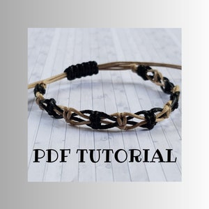 Peut inclure: Un bracelet tressé noir et beige avec un motif de nœuds. Le bracelet est sur une surface blanche avec le texte "PDF TUTORIAL".