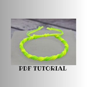 May include: A green and yellow braided friendship bracelet with a knot at the end. PDF TUTORIAL is written below the bracelet.