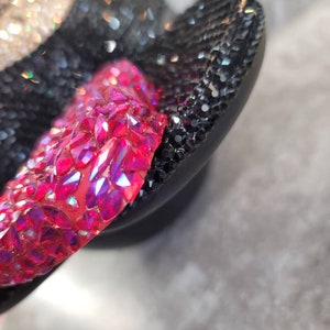 Puede incluir: Primer plano de un par de chanclas negras con pedrer&iacute;a rosa y transparente. Las chanclas est&aacute;n cubiertas de pedrer&iacute;a.