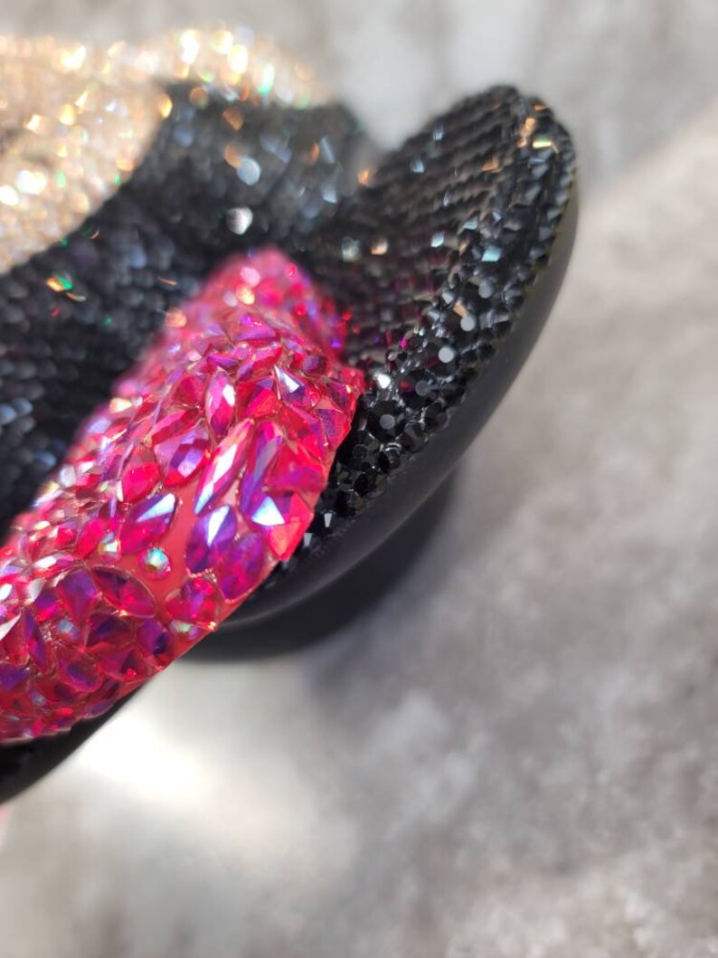Puede incluir: Primer plano de un par de chanclas negras con pedrer&iacute;a rosa y transparente. Las chanclas est&aacute;n cubiertas de pedrer&iacute;a.