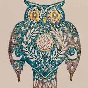 May include: A teal owl illustration with gold and white accents. The owl features intricate patterns, including stars, moons, and floral designs. The owl's eyes are gold, and the overall design has a folk art aesthetic.