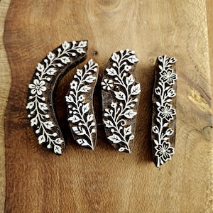 May include: Four dark brown wooden printing blocks featuring intricate white floral and vine carvings. The set includes one curved block, two tapered leaf-shaped blocks, and one rectangular block, all displaying detailed botanical patterns.