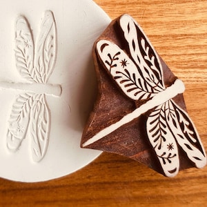 May include: A white ceramic mug with a black handle and the text "But First, Coffee" in a handwritten style. The mug is on a white surface. The mug is likely for hot beverages.