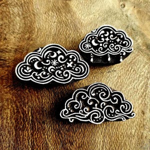 May include: Three black and white cloud-shaped printing blocks featuring intricate carved patterns of swirls, stars, and crescent moons. Each block displays a distinct celestial design with fine lines and decorative elements etched into the surface.