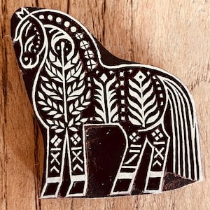 May include: A white ceramic mug with a black handle and the text "But First, Coffee" in a black, bold font. The mug is sitting on a wooden surface. The mug is approximately 4 inches tall.