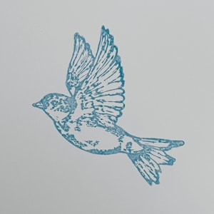 Puede incluir: Ilustración detallada de un pájaro en vuelo, en un tono azul verdoso apagado. Las alas del pájaro están extendidas, mostrando intrincados detalles de las plumas. La obra de arte está sobre un fondo blanco liso, enfatizando la forma y el movimiento del pájaro.