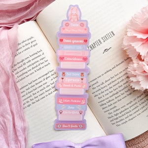 May include: A stack of colorful book-themed bookmarks with pink and purple accents. The bookmarks feature titles like "Taste", "Good Graces", "Coincidence", "Bed Charm", "Slim Pickins", "Juno", "Lie to Girls", and "Don't Smile".