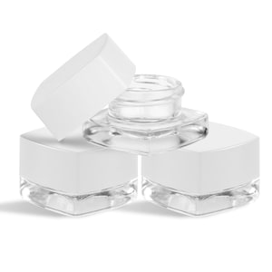 May include: Three clear glass jars with white square lids. One jar has its lid slightly ajar, revealing the clear glass container. The jars are arranged on a white background, with soft shadows.