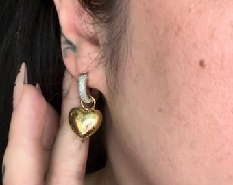Pendientes de aro plateados brillantes con dijes de corazón y estrella dorados: joyería moderna y de estilos diferentes.