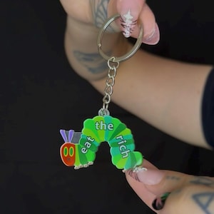 Porte-clés acrylique « Eat The Rich » - breloque de sac colorée inspirée des dessins animés rétro avec une chenille - porte-clés à message politique