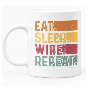 May include: White ceramic mug featuring a vintage-style graphic that reads "Eat, Sleep, Wire, Repeat!" in a colourful, layered design.