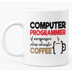 May include: White ceramic mug with the text "COMPUTER PROGRAMMER if unresponsive please administer COFFEE" in black, red, and brown. A coffee cup graphic is also included. The mug has a white handle.
