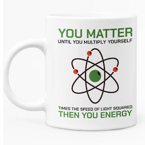 May include: White ceramic mug with a green and black atom illustration and the text "YOU MATTER UNTIL YOU MULTIPLY YOURSELF TIMES THE SPEED OF LIGHT SQUARED THEN YOU ENERGY".