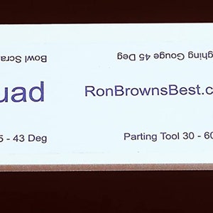 May include: White plastic tool with the text "Quad" and "RonBrownsBest.com". The tool is labeled with different types of woodturning tools and their corresponding angles, including skew, parting tool, roughing gouge, and bowl scraper.