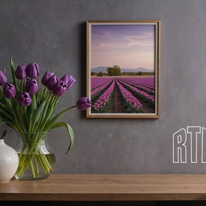 May include: A framed photograph of a field of purple tulips with a row of trees in the distance. The photo is hanging on a gray wall with a vase of purple tulips in the foreground.
