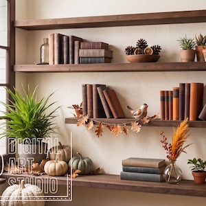 May include: Three dark wood floating shelves mounted on a cream wall, displaying rows of vintage books, small potted succulents, pinecones in a bowl, a metal watering can, a bird figurine, dried foliage, pumpkins, and pillar candles.
