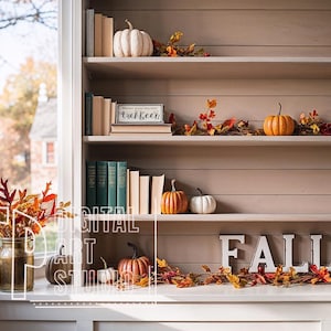 May include: A cozy autumn-themed bookshelf display. The shelves are adorned with pumpkins, fall foliage, and stacks of books. A sign reads "Let's Stay In". The word "FALL" is spelled out in large white letters on the bottom shelf.