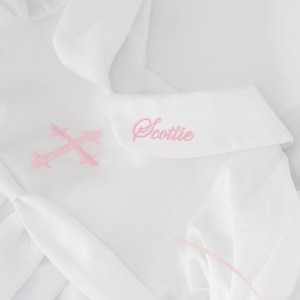 Close-up of soft pink cross embroidery and monogram stitched on collar.