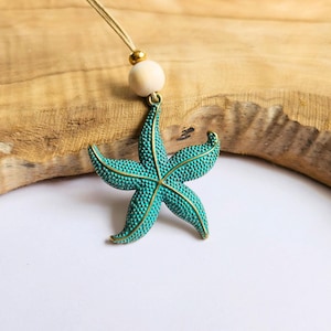 May include: A teal blue starfish pendant necklace with a wooden bead on a brown cord.