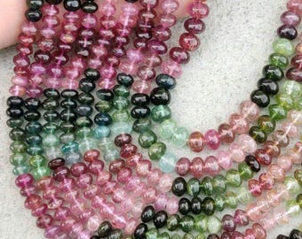 May include: Strands of colorful tourmaline beads in shades of pink, green, black, and clear. The beads are small and round, strung together to create a necklace or bracelet. The beads are a mix of colors, creating a vibrant and eye-catching design.
