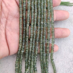 May include: A strand of green gemstone beads, likely aventurine, with a faceted, cylindrical shape. The beads are strung on a clear thread and are approximately 4mm in diameter.