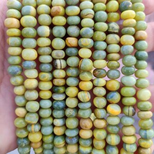 May include: A strand of yellow and green gemstone beads. The beads are round and have a smooth, polished finish.