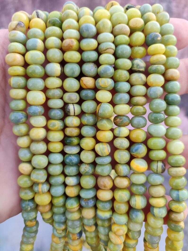 May include: A strand of yellow and green gemstone beads. The beads are round and have a smooth, polished finish.