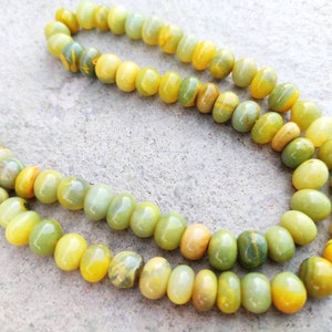 May include: A strand of yellow and green gemstone beads. The beads are round and have a smooth, polished finish.