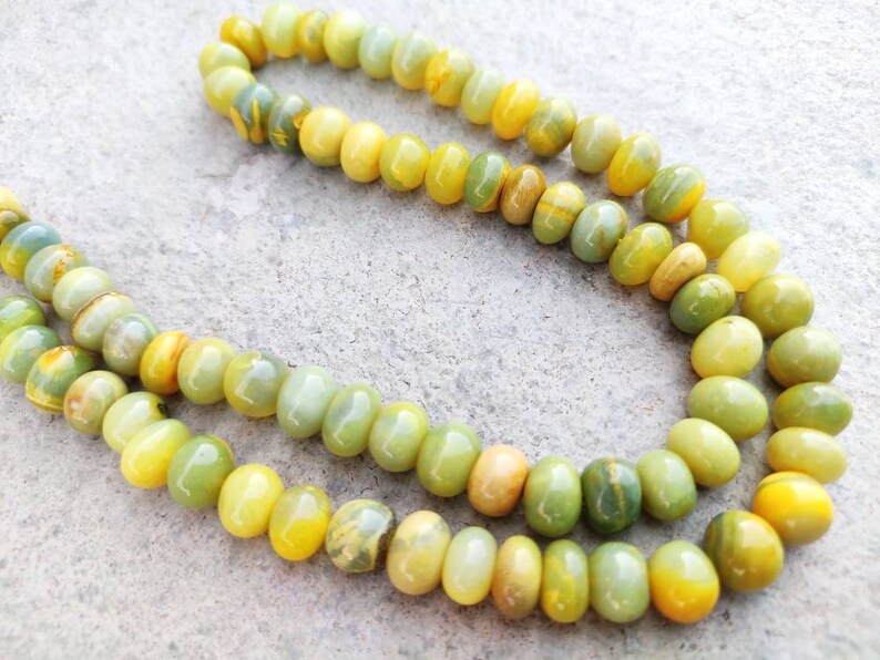 May include: A strand of yellow and green gemstone beads. The beads are round and have a smooth, polished finish.