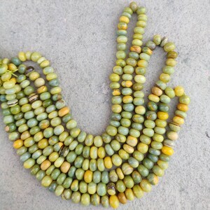 May include: A strand of green and yellow gemstone beads. The beads are round and have a smooth, polished finish.