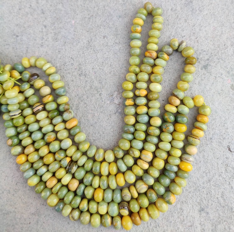 May include: A strand of green and yellow gemstone beads. The beads are round and have a smooth, polished finish.