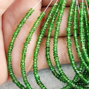 May include: A strand of green gemstone beads, likely peridot, strung on thin wire. The beads are faceted and have a slightly irregular shape. There are multiple strands of beads in the image, all of the same colour and style.