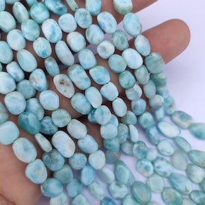 Puede incluir: Hebras de cuentas de piedra preciosa larimar azul claro. Las cuentas ovaladas tienen una superficie pulida y varían en color de azul pálido a medio, con vetas blancas. Ideales para la creación de joyas.