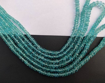 May include: Strands of faceted, light blue gemstone beads. The beads vary in size, creating a layered effect. The beads are strung together, forming multiple strands. The background is a mix of white and black.