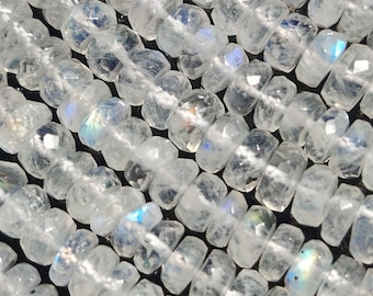 May include: Close-up of strands of faceted, clear moonstone beads. The beads are strung together, displaying a range of iridescent colors. The beads are cut with multiple facets, reflecting light and creating a sparkling effect. The overall theme is jewelry making.