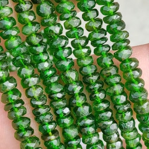 May include: A strand of faceted green gemstone beads. The beads are small and round, with a smooth, polished finish.
