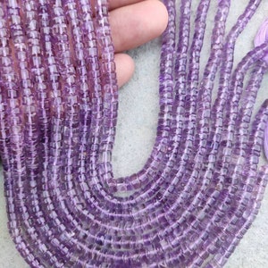May include: A strand of amethyst beads, each bead is a square shape with a light purple color. The beads are strung on a thin thread and are approximately 6mm in size.