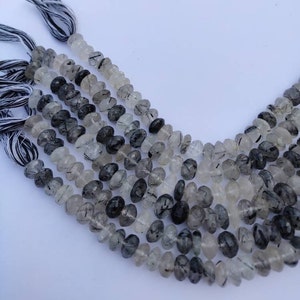May include: A strand of black tourmaline beads with clear quartz inclusions. The beads are faceted and have a natural, irregular shape. The strand is approximately 16 inches long.