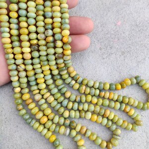 May include: A strand of green and yellow gemstone beads. The beads are round and have a smooth, polished finish.
