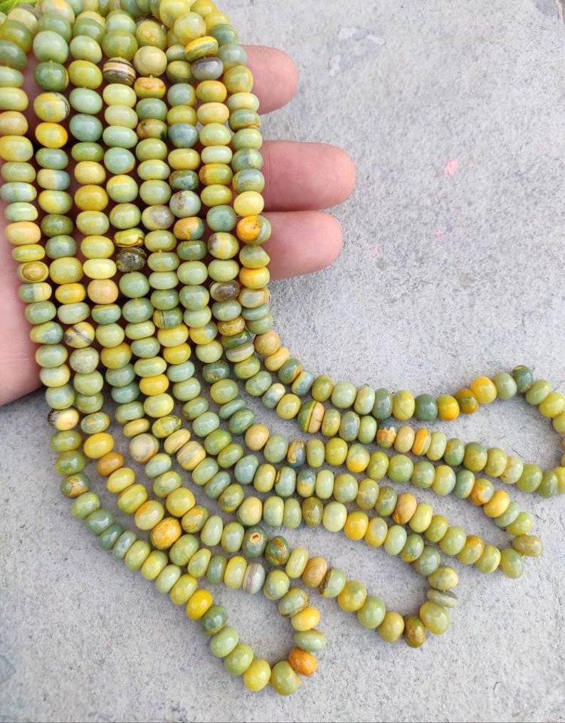 May include: A strand of green and yellow gemstone beads. The beads are round and have a smooth, polished finish.