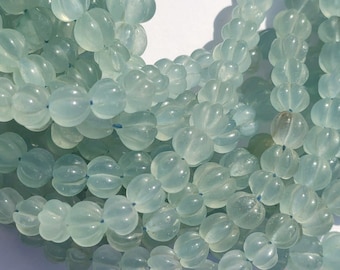 May include: A strand of light blue, translucent, faceted beads. The beads are oval shaped and have a slightly bumpy texture.