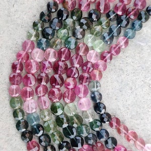 Op de afbeelding: Een streng facetgeslepen ronde kralen in tinten roze, groen en blauw. De kralen zijn gerangschikt in een verloop, met de roze kralen bovenaan en de blauwe kralen onderaan.