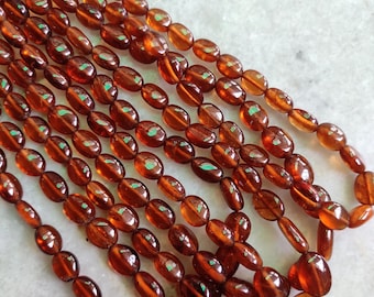 May include: A strand of brown oval-shaped gemstone beads. The beads are smooth and polished, with a slight sheen.