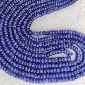 Può includere: Una collana di perline di pietra preziosa sfaccettata blu scuro. Le perline sono piccole e rotonde e sono infilate su un filo trasparente.